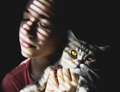 Girl holding cat in partial light